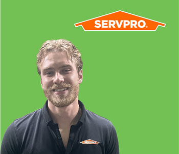 SERVPRO employee with light hair wearing a black shirt in front of a green background