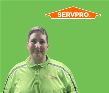 SERVPRO employee with dark hair wearing a green shirt in front of a green background