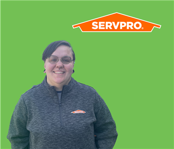 SERVPRO employee with grey sweater and dark hair in front of green background