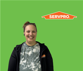 SERVPRO employee with light hair wearing a black jacket in front of a green background