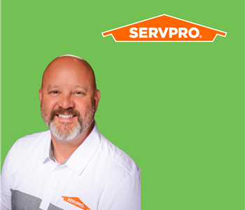 a man with a white shirt in front of a SERVPRO background