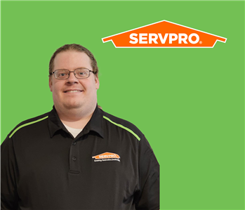 SERVPRO employee with light hair wearing a black shirt in front of a green background