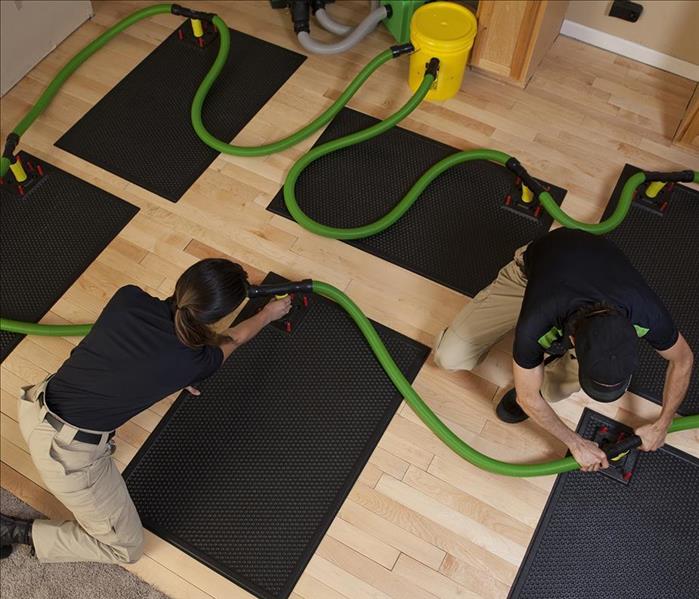 SERVPRO worker setting up equipment to aerate the wooden floor 
