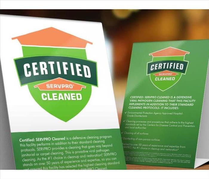 Table tent sings describing the certified: SERVPRO Cleaned program on top of a wooden table.